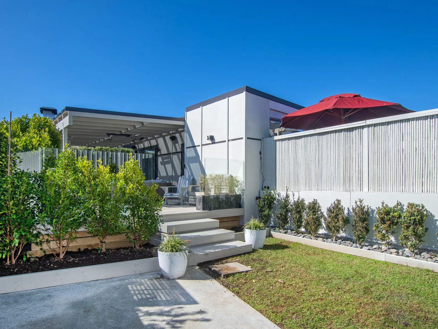 Una zona exterior con una terraza de madera y plantas en Sun Kissed Pool Villa - Mangawhai Heads