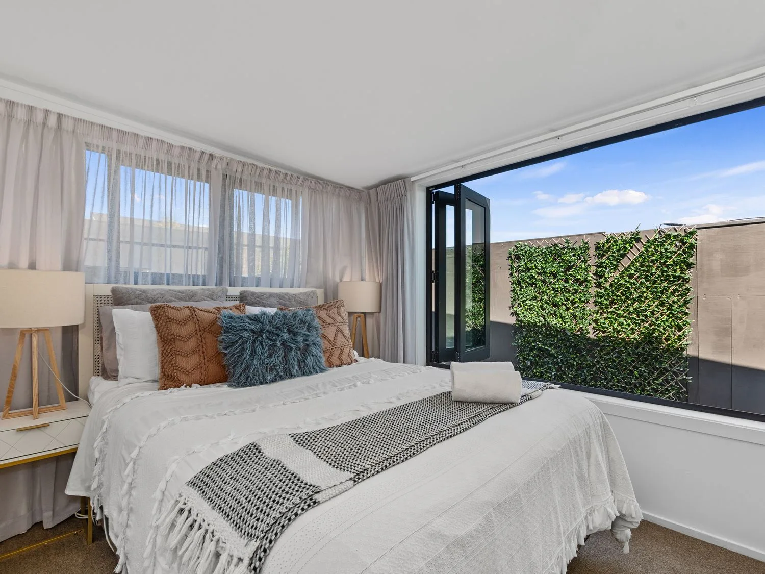 Un dormitorio con una cama y una ventana en Sun Kissed Pool Villa - Casa de vacaciones en Mangawhai, Mangawhai Heads
