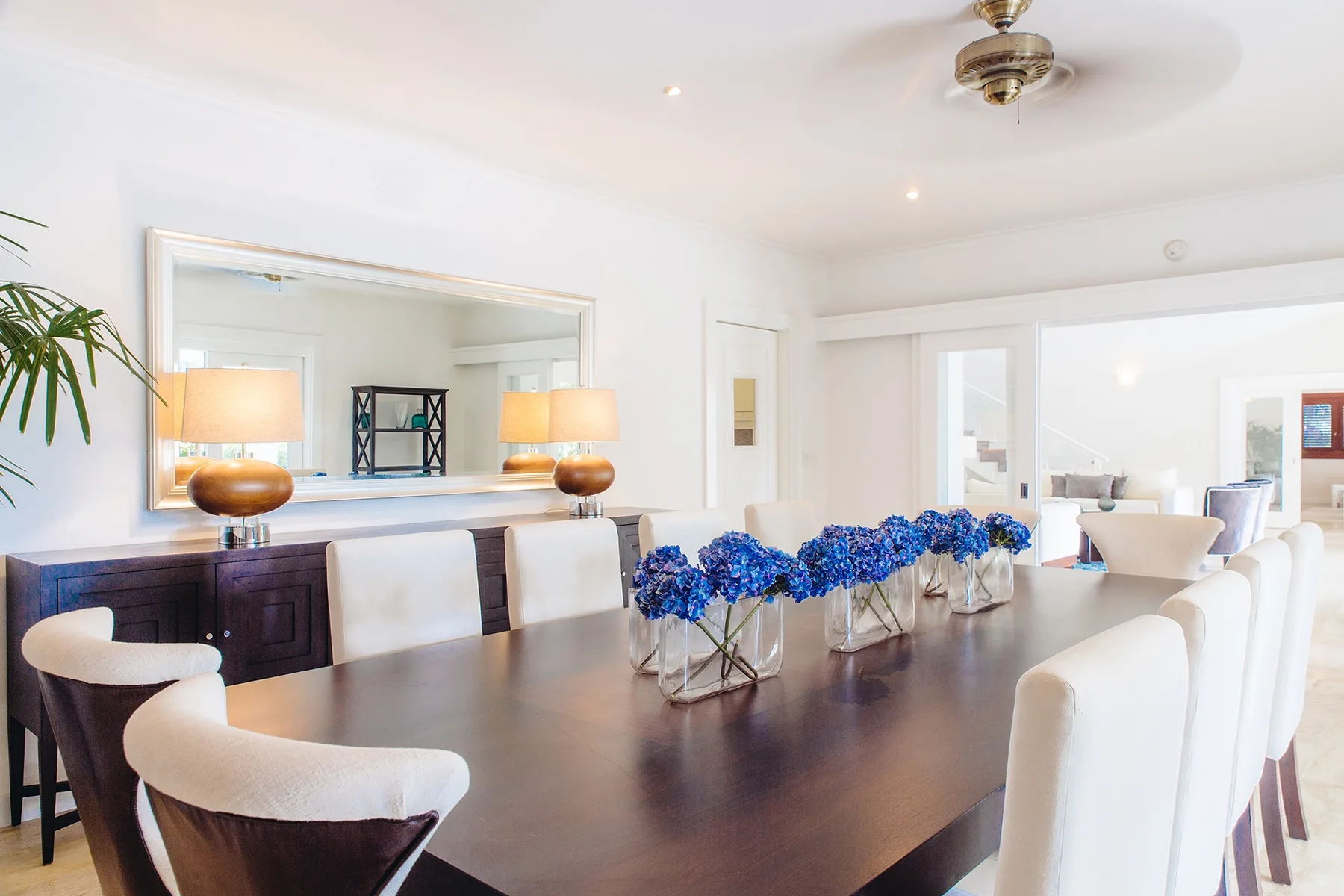 Un comedor luminoso con una mesa larga y arreglos florales azules.