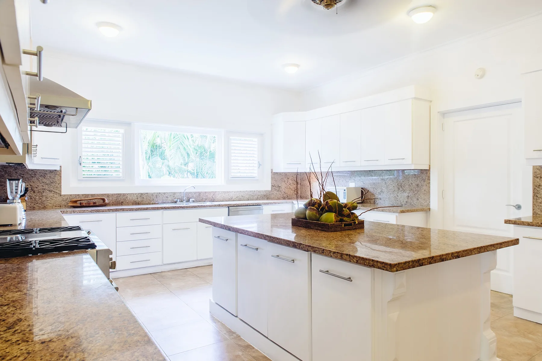 Una cocina luminosa con gabinetes blancos y una isla central.