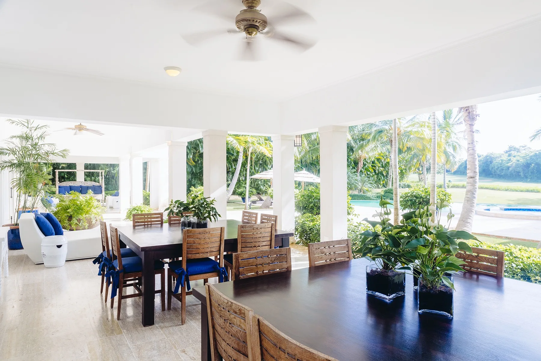 Un comedor luminoso con mesas largas de madera y vistas a la vegetación tropical.
