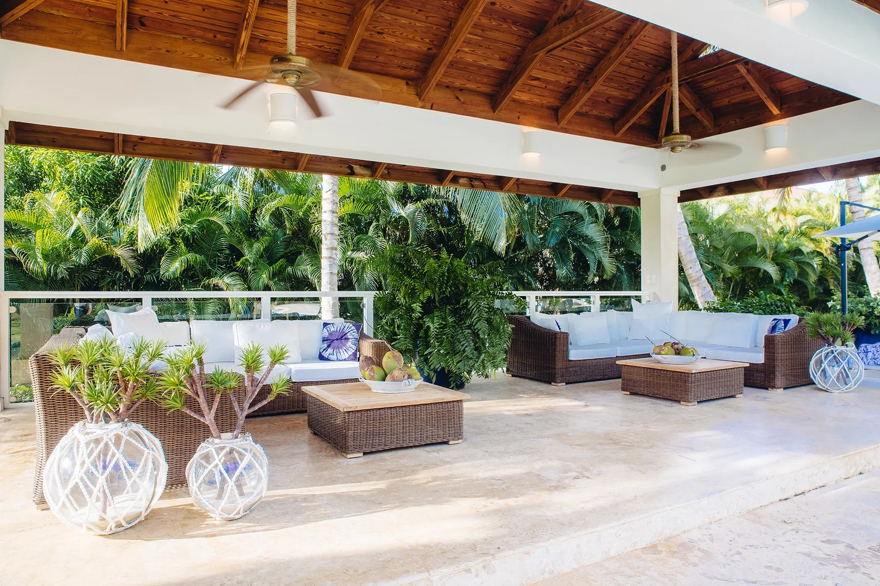 Una zona de estar exterior cubierta da a una frondosa vegetación tropical.