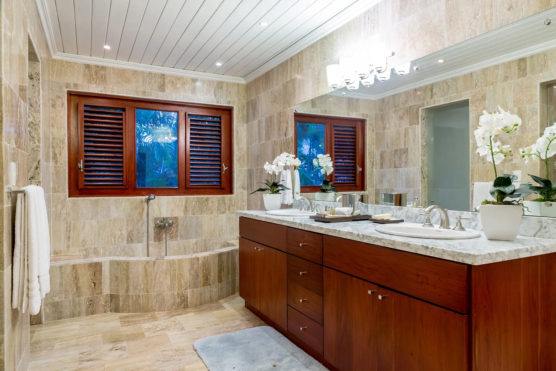 Un baño con un tocador largo y una ventana con persianas de madera.