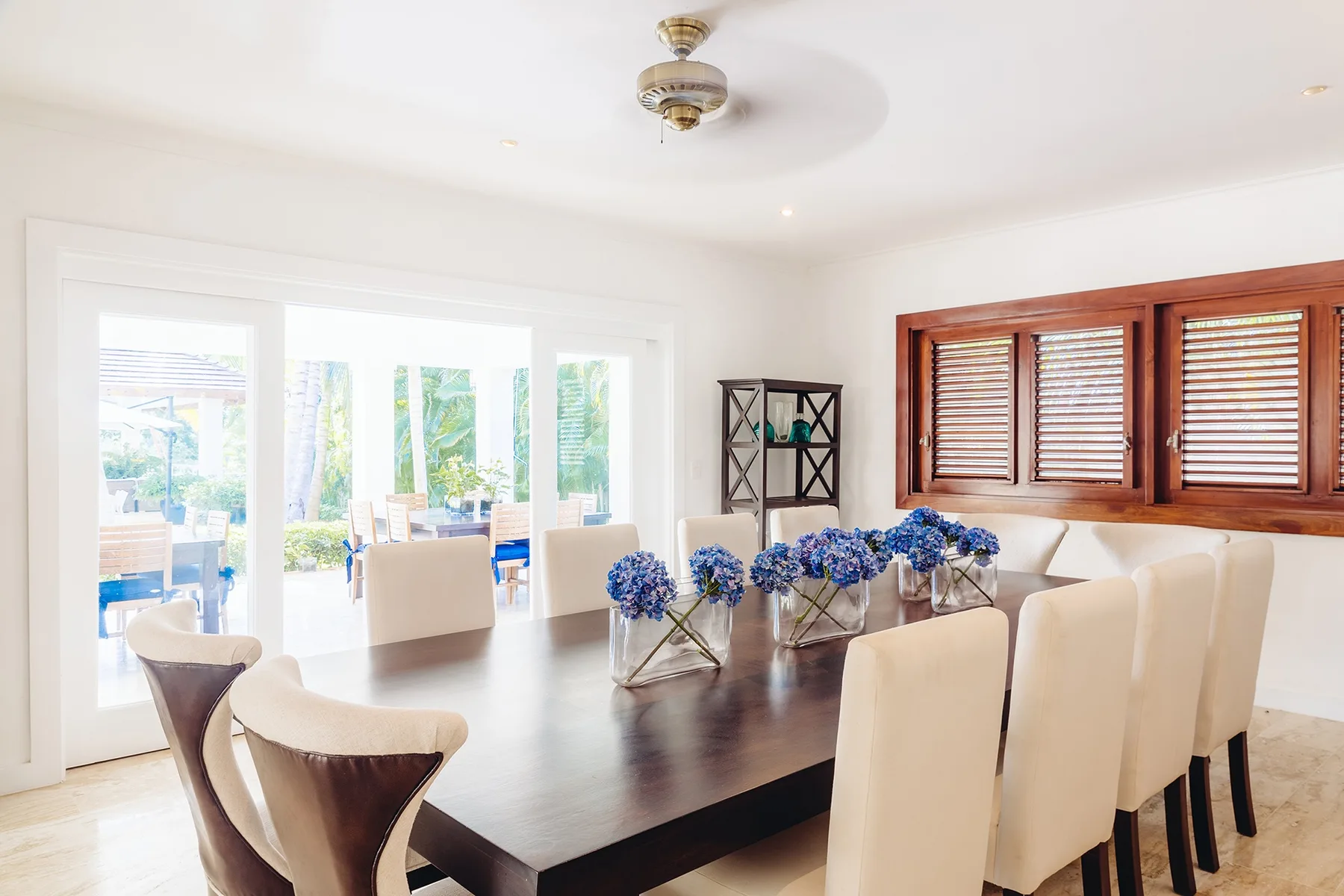 Un comedor luminoso con una mesa larga y flores azules.