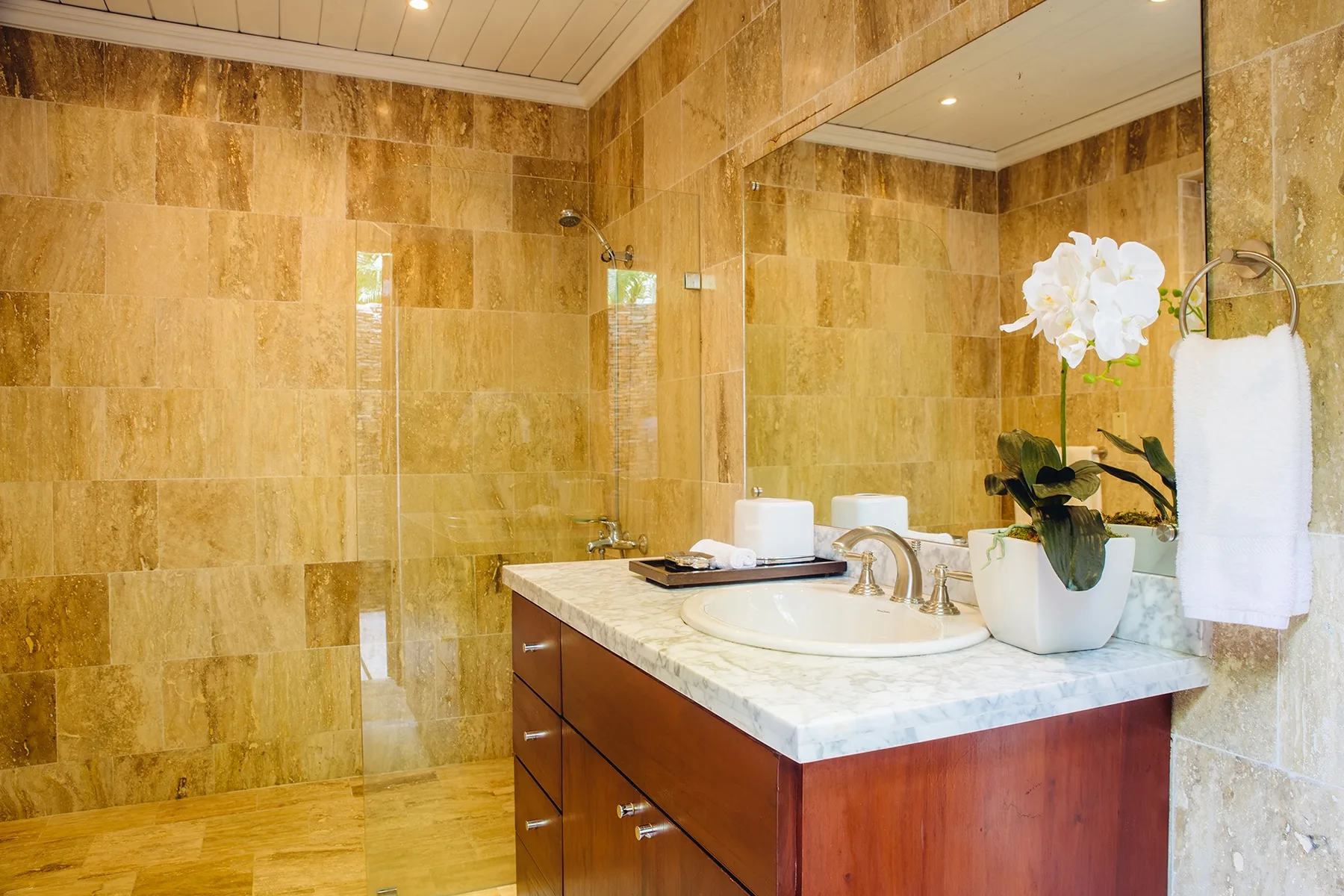 Un baño alicatado con lavabo, espejo grande y ducha.