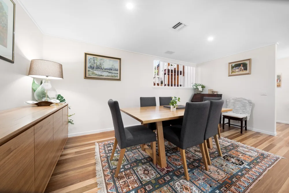 Comedor con una mesa de madera y varias sillas sobre una alfombra.