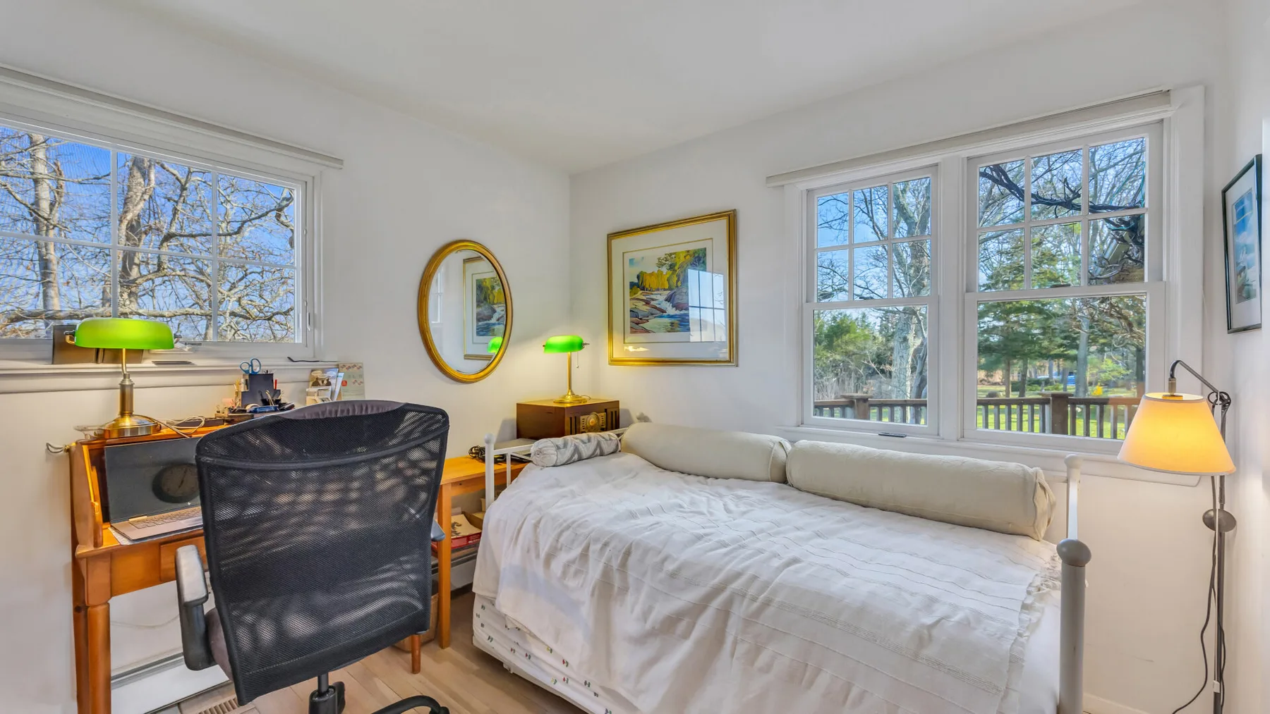 A bright bedroom with a bed, desk, and large windows.