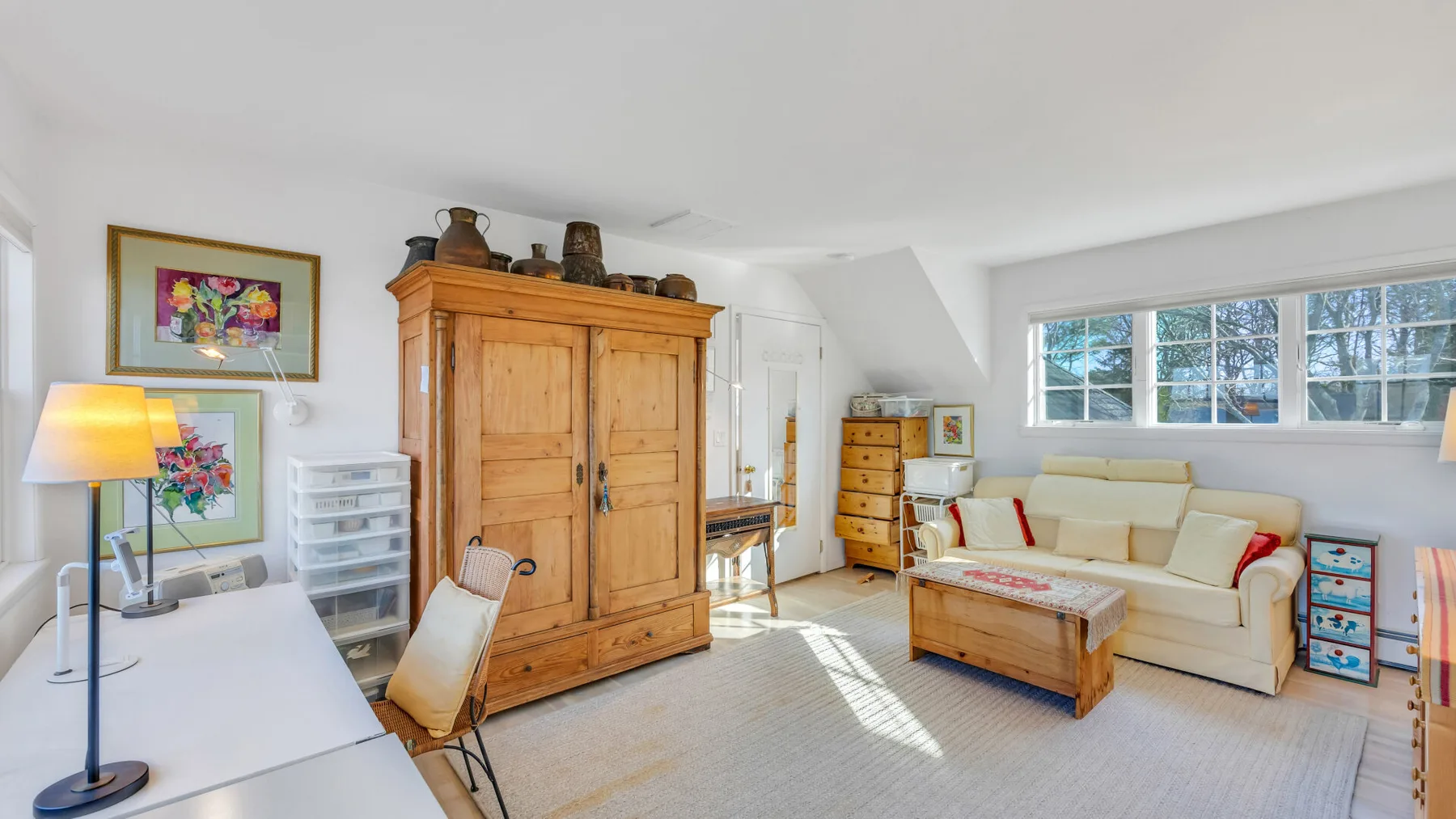 A bright living room with a wooden cabinet, seating, and a coffee table.