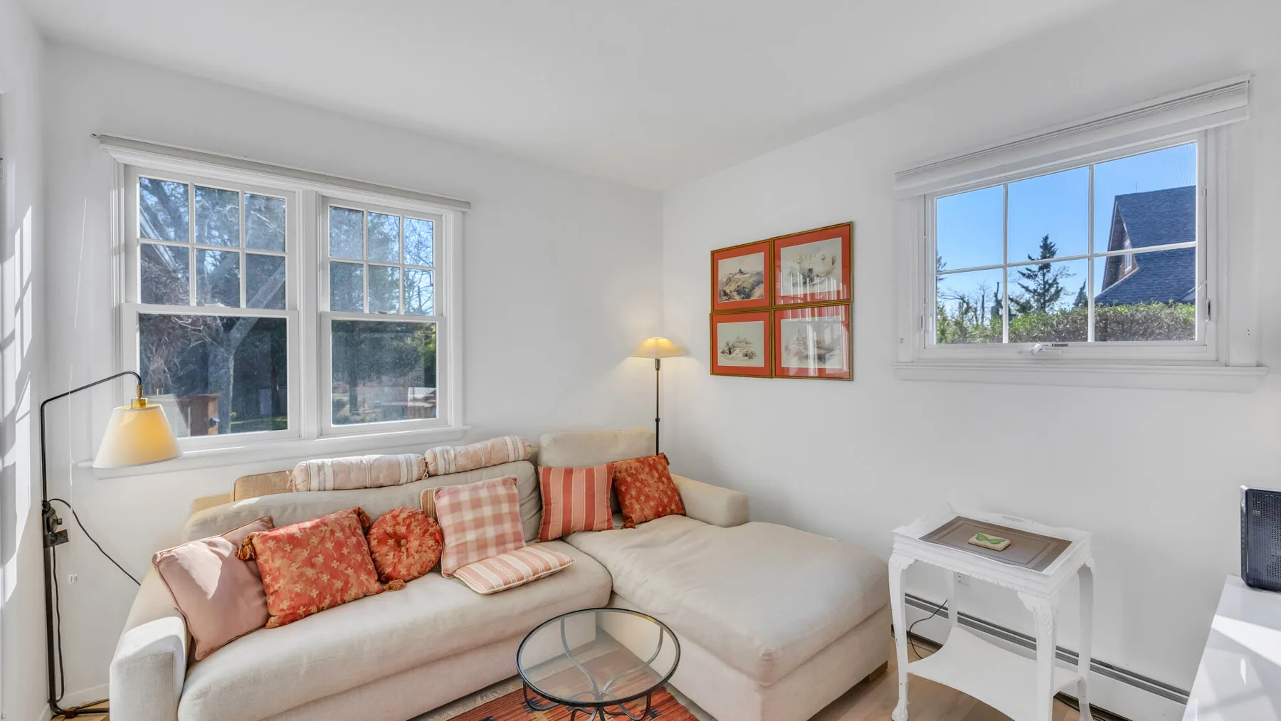 A bright living room with a sectional sofa beside two windows.