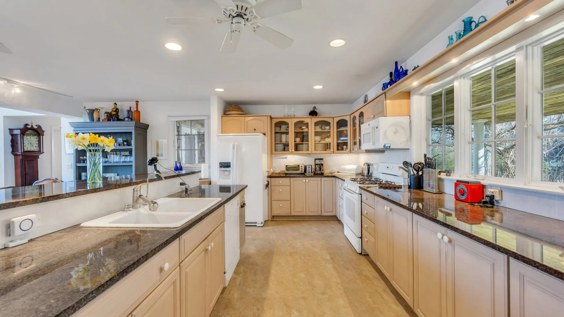 A bright kitchen with long counters, light cabinets, and large windows.