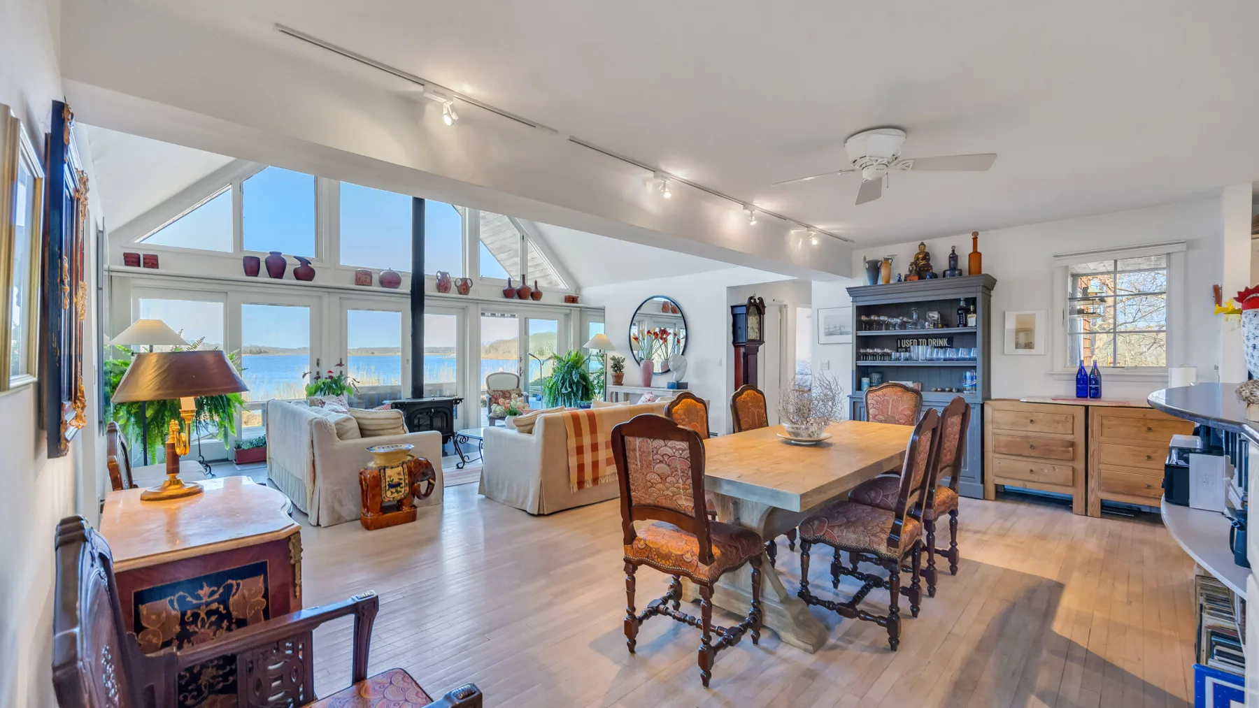 A bright open-plan living and dining room with large windows overlooking the water.