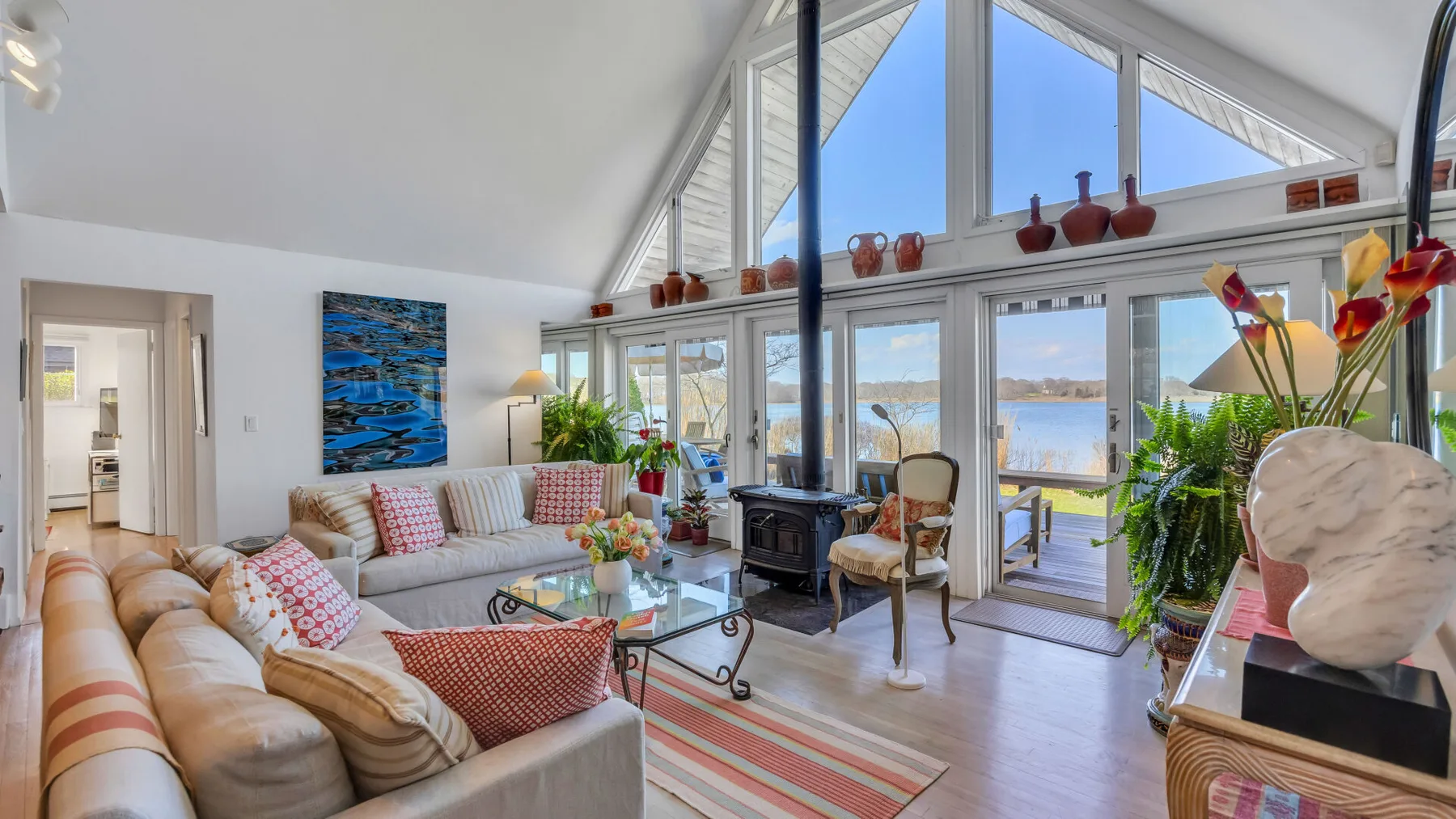 A bright living room with sloped windows, seating, and a view of the water.