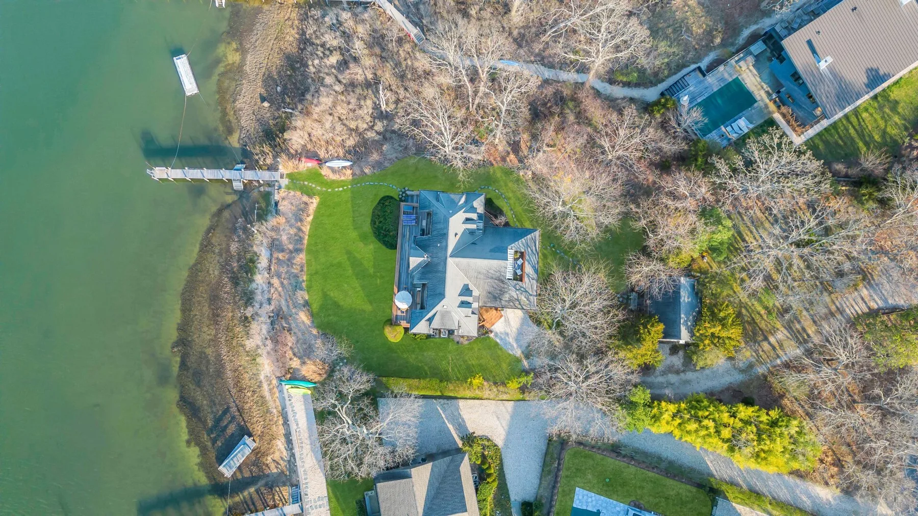 An aerial view of a lakeside home, lawn, and dock.