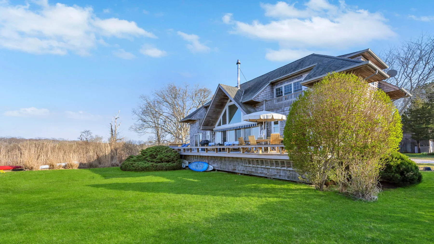 A large house stands beside a broad green lawn and patio.