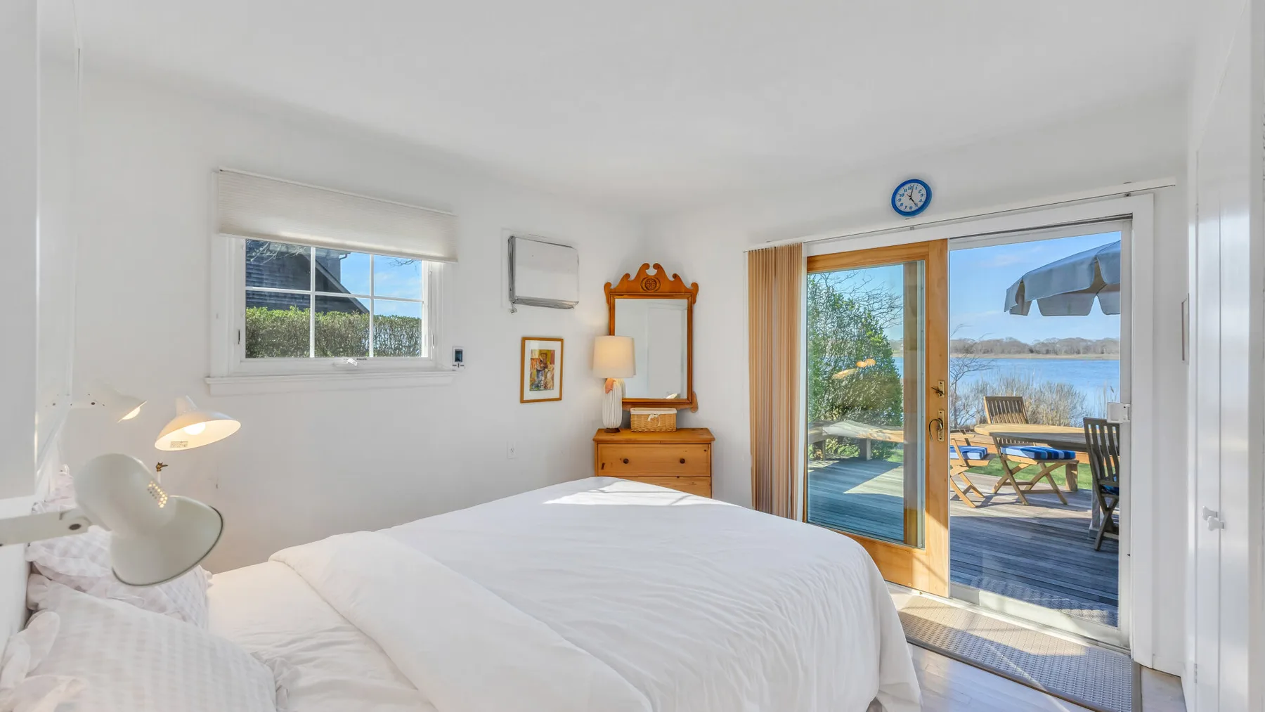 A bright bedroom with a bed and sliding glass doors opening onto a deck.