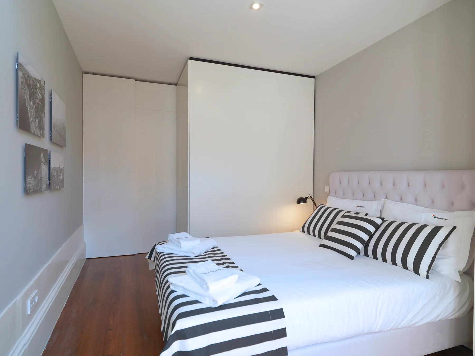 A bedroom with a white bed, striped pillows, and folded towels.
