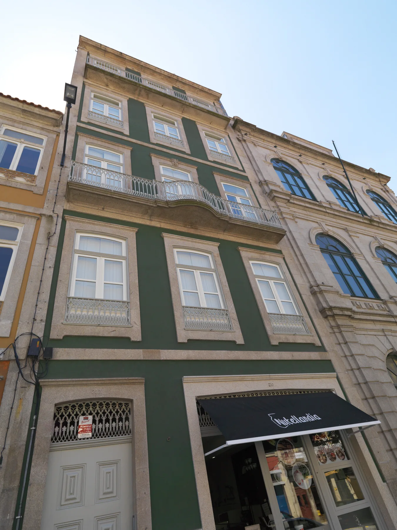 A dark green multi-story storefront stands between neighboring stone façades.