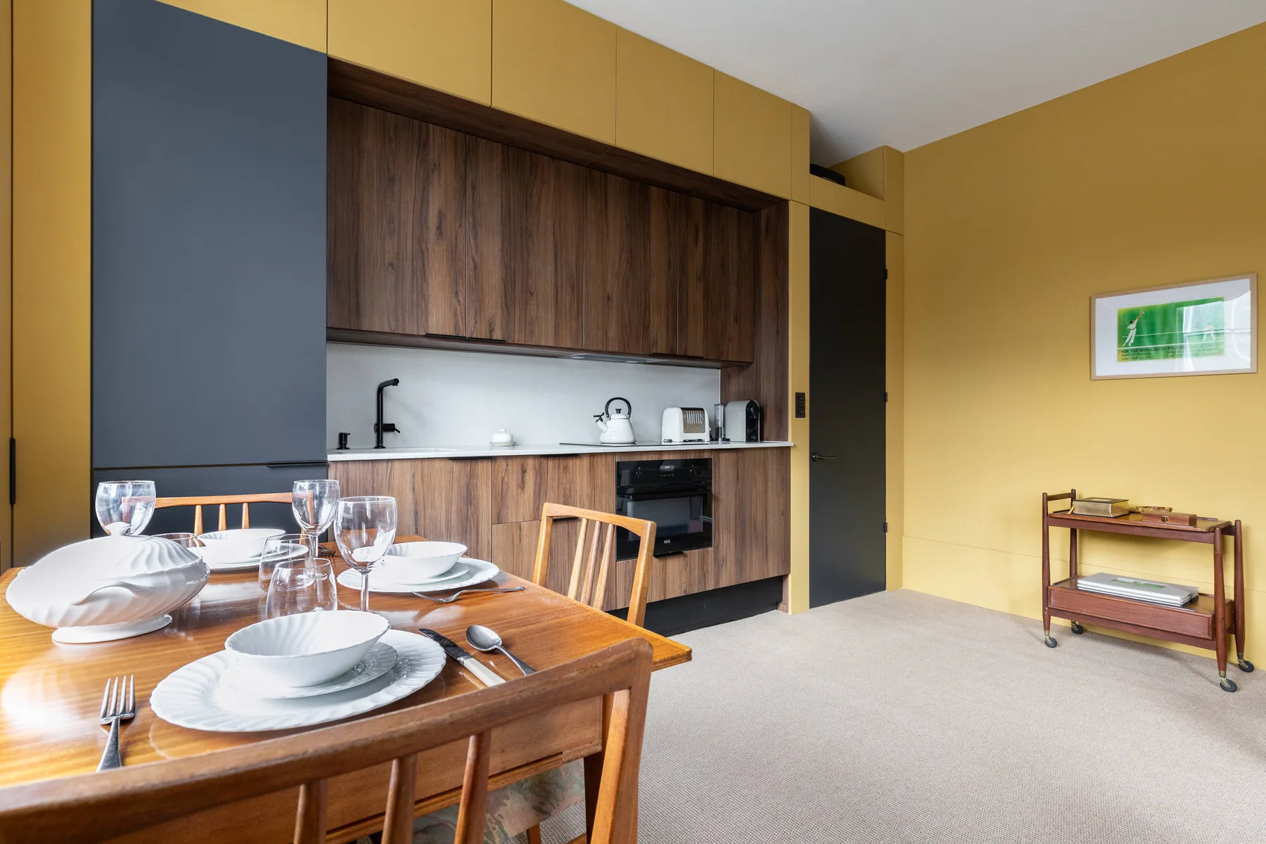 Comedor con la mesa puesta junto a una cocina compacta.