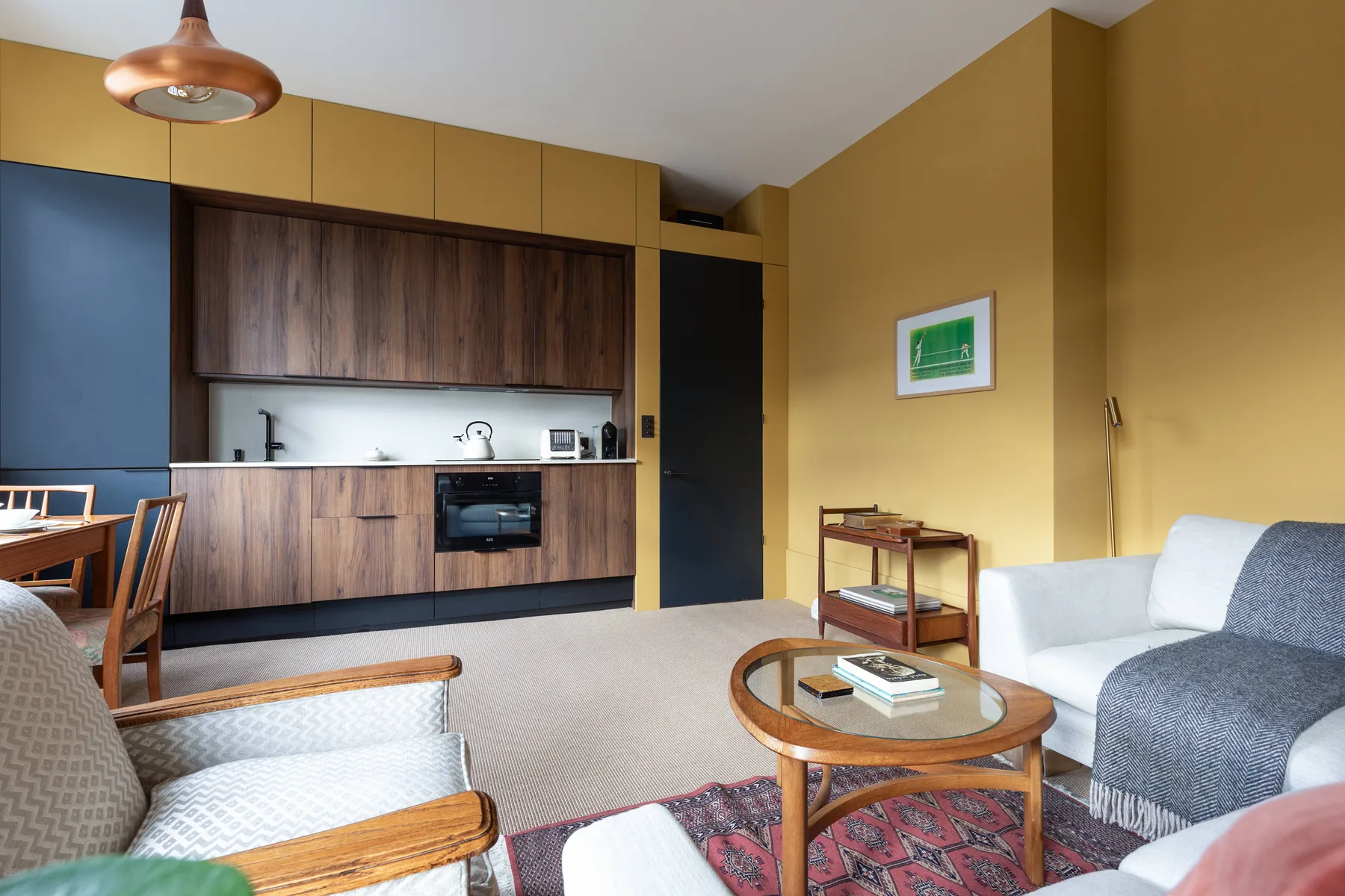 Una sala de estar con asientos y una mesa de centro redonda junto a una cocina abierta.