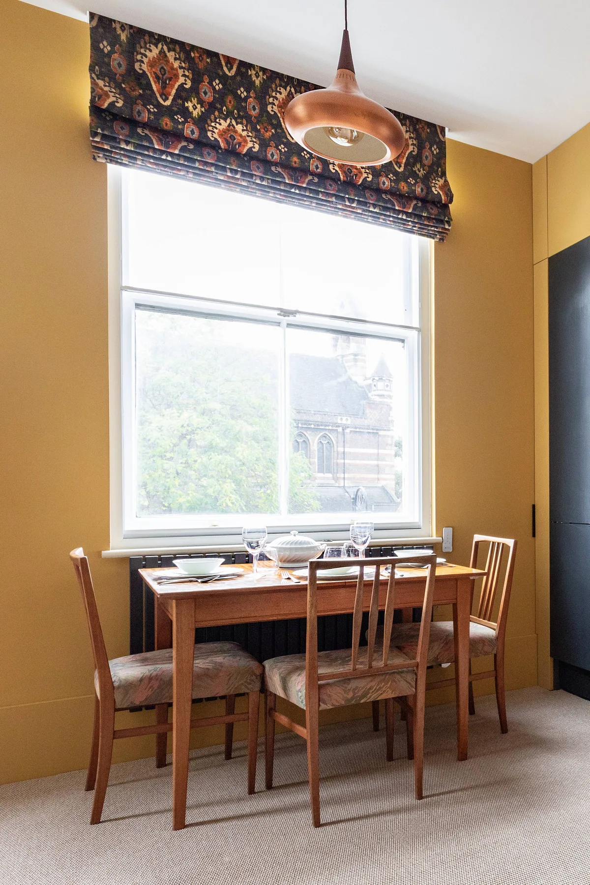 Un comedor con una mesa de madera y sillas junto a una ventana grande.