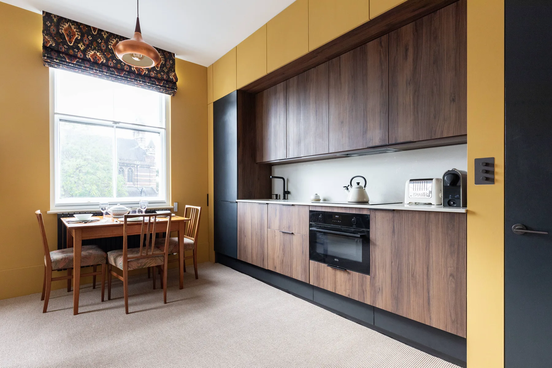 Una cocina compacta con gabinetes de madera oscura y una mesa junto a la ventana.