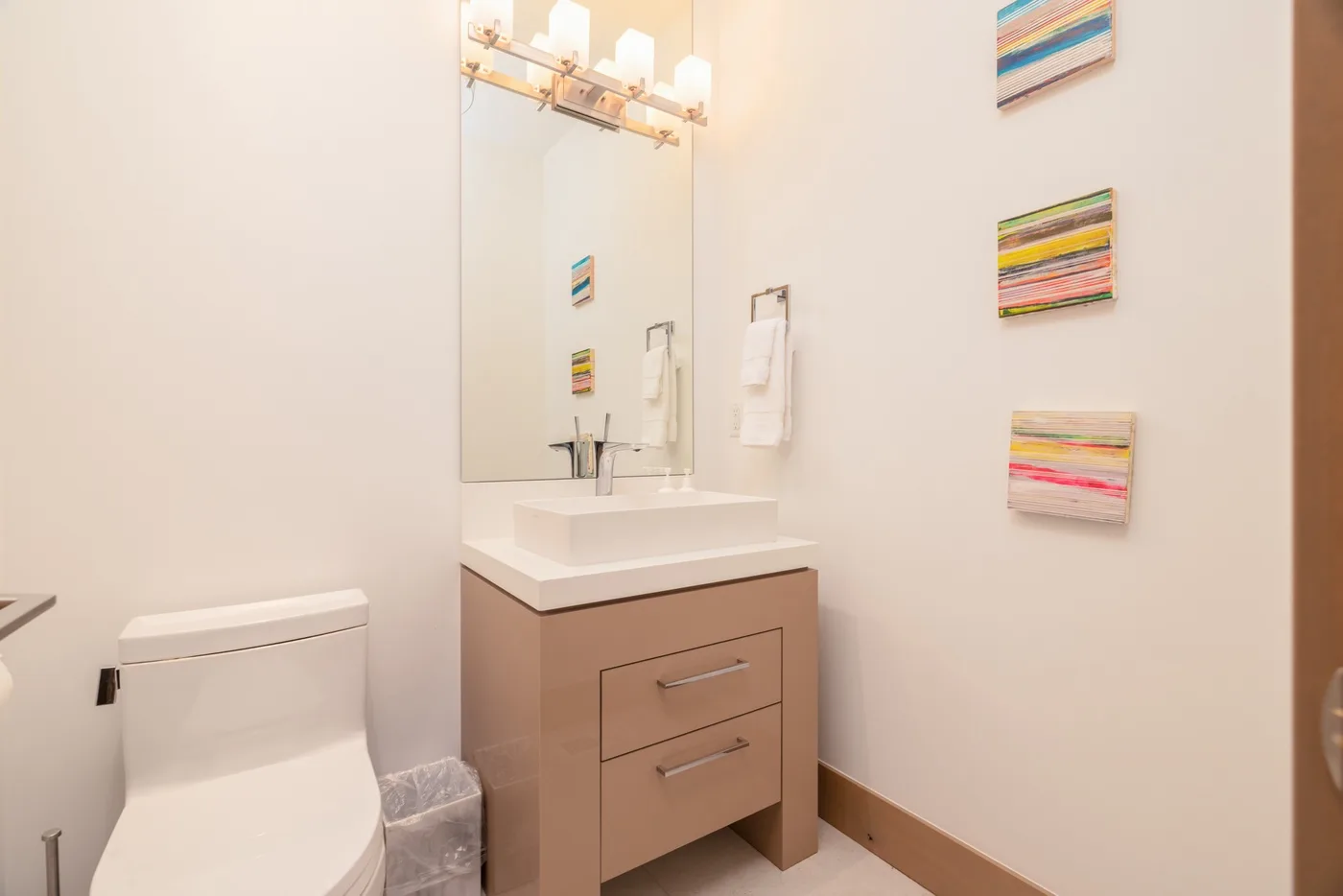 A bathroom vanity with a sink and mirror beside a toilet.