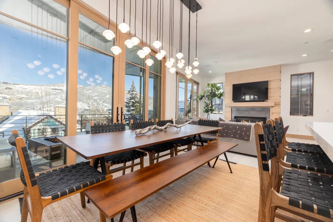 A dining area with a long wooden table and large windows overlooking a snowy landscape.