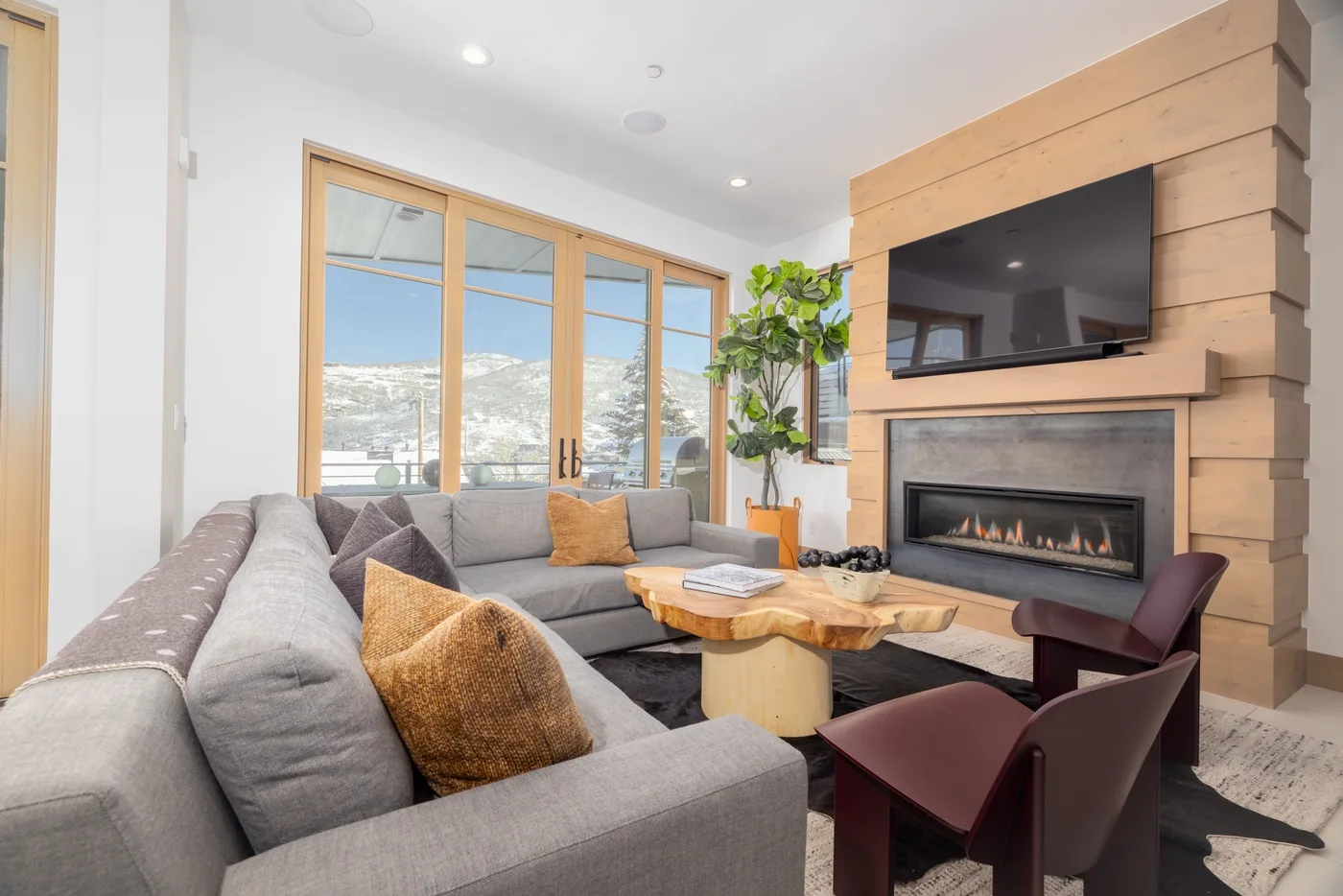 Una sala de estar con asientos grises, una chimenea y ventanas grandes.