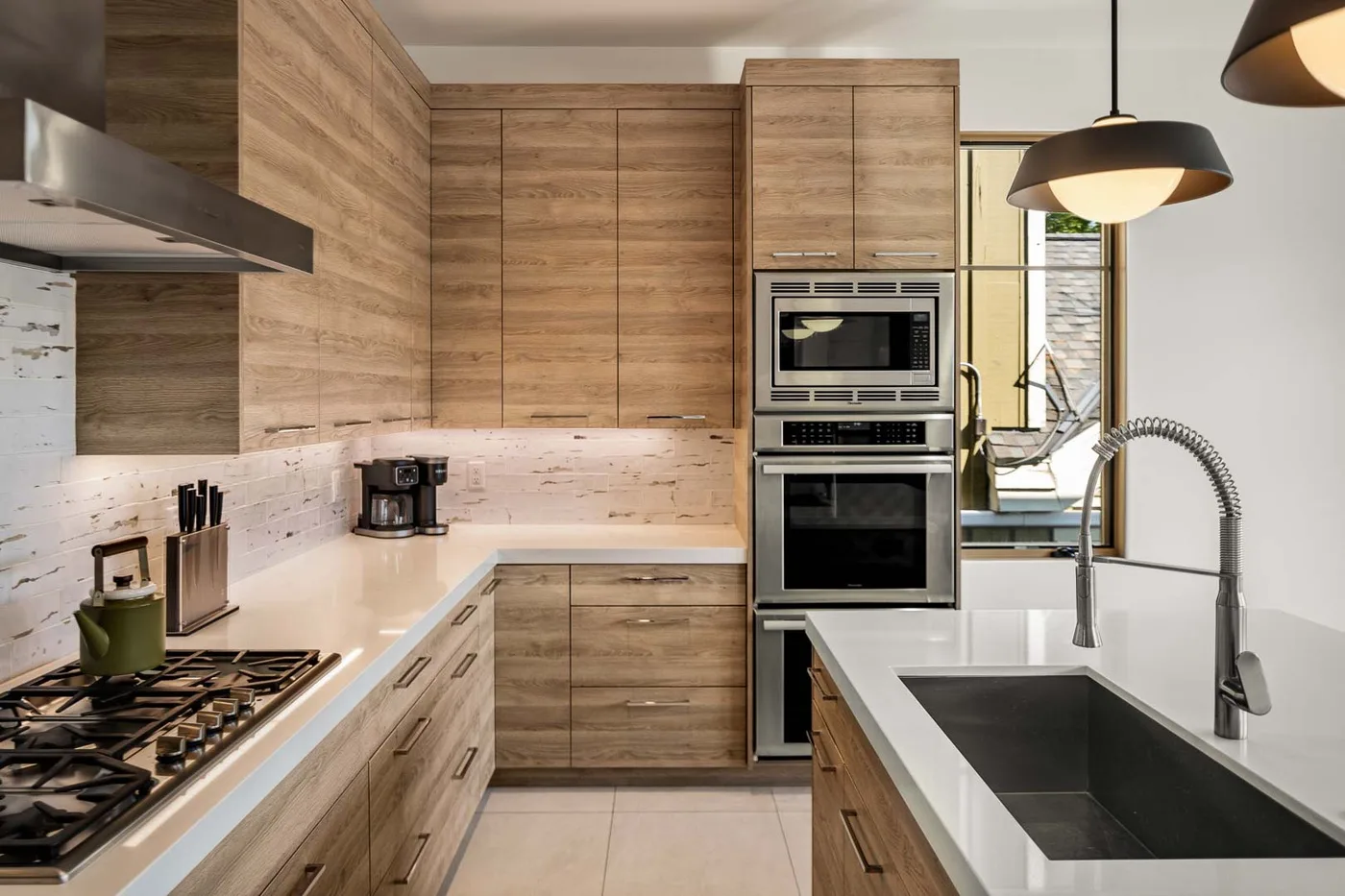 A modern kitchen with wood cabinets, built-in ovens, and a central island.