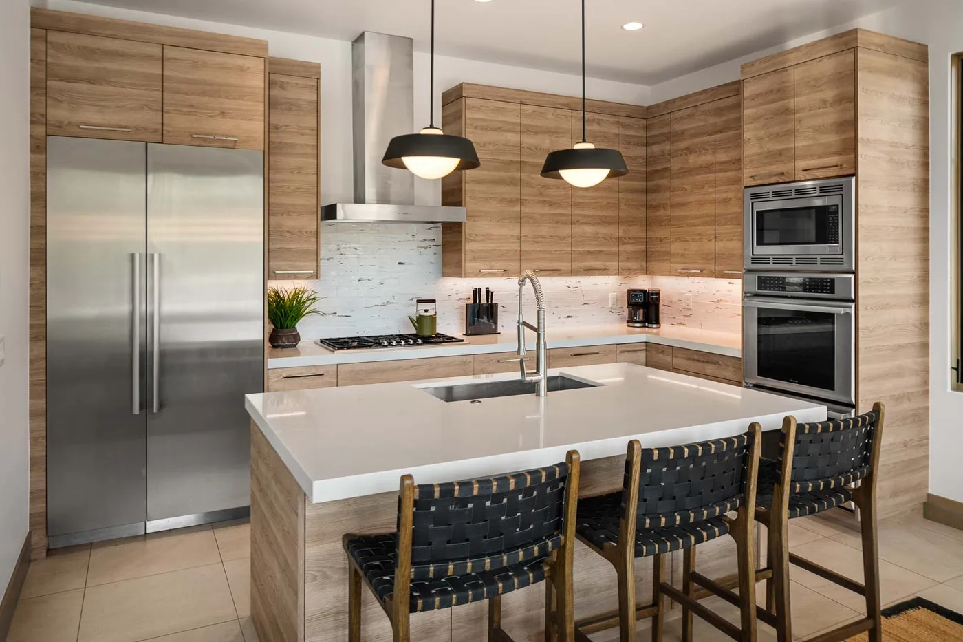 A modern kitchen with a large island, wood cabinets, and stainless steel appliances.