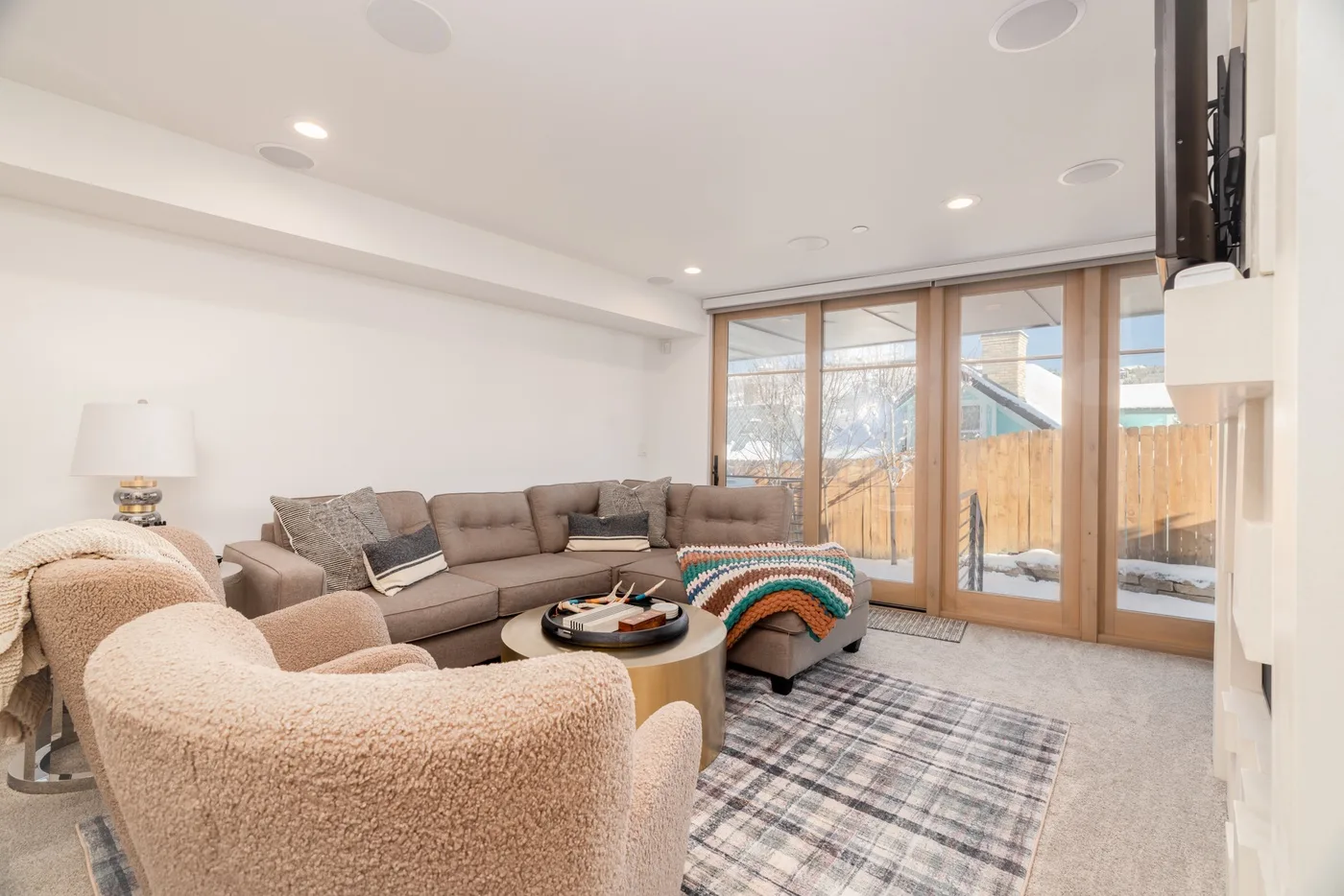 A bright living room with seating arranged around a coffee table beside large windows.