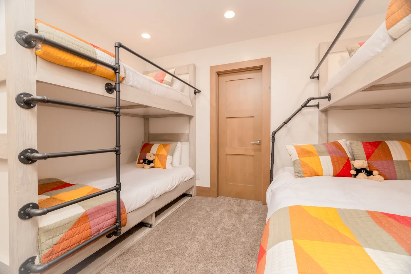 A bedroom with two bunk beds and colorful bedding.