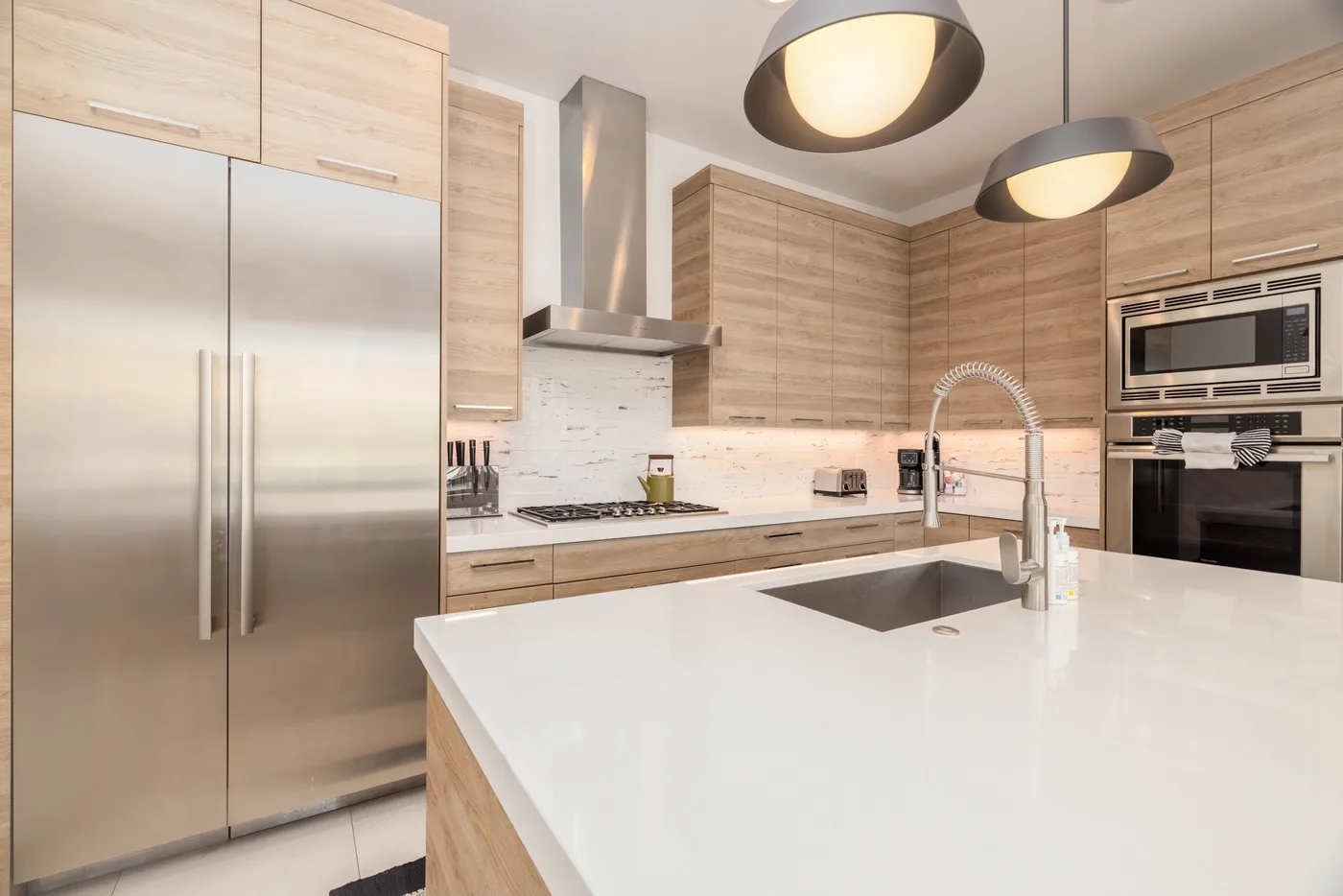 A modern kitchen with a large island, stainless steel appliances, and wood cabinetry.