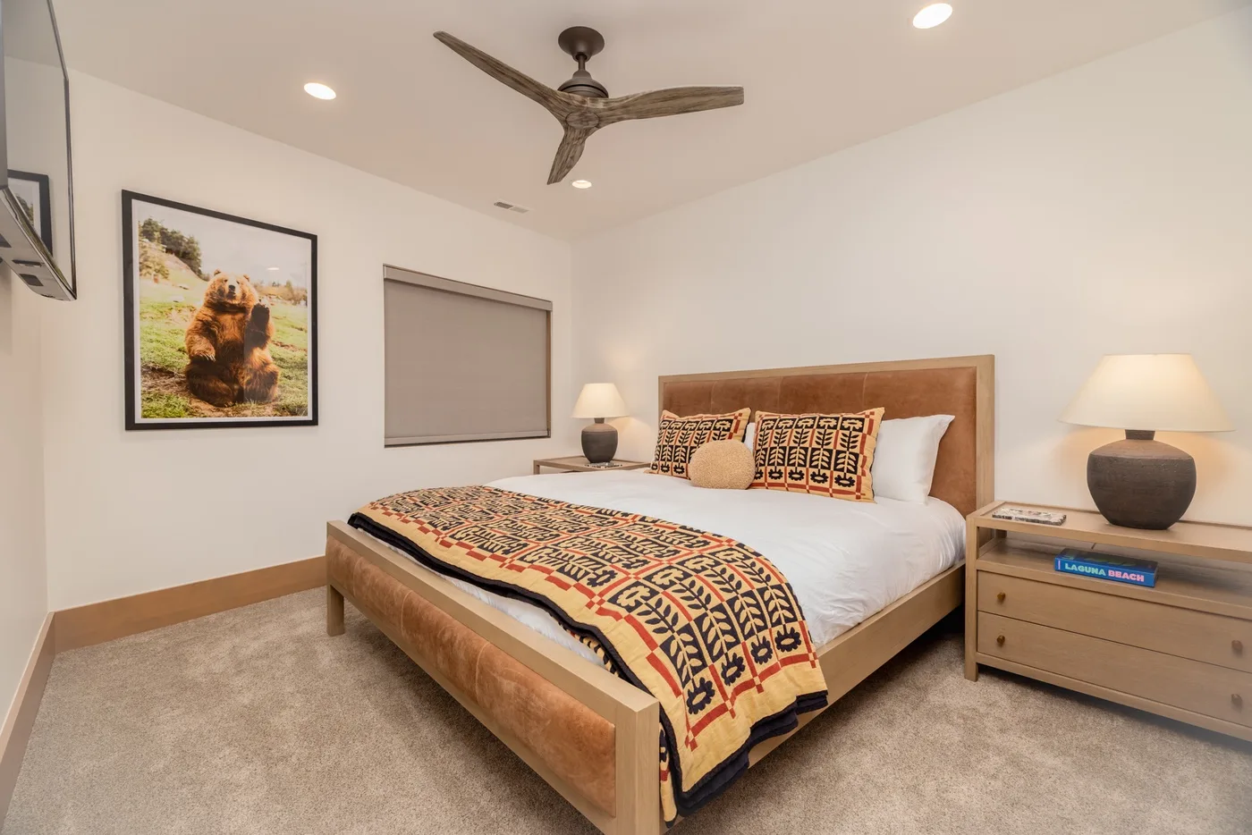 A bedroom with a neatly made bed and patterned blanket.