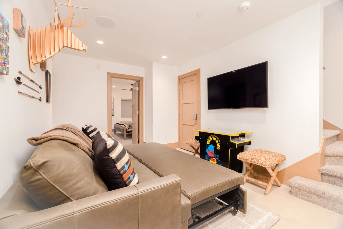 A bright living room with seating, a wall-mounted television, and a small table.