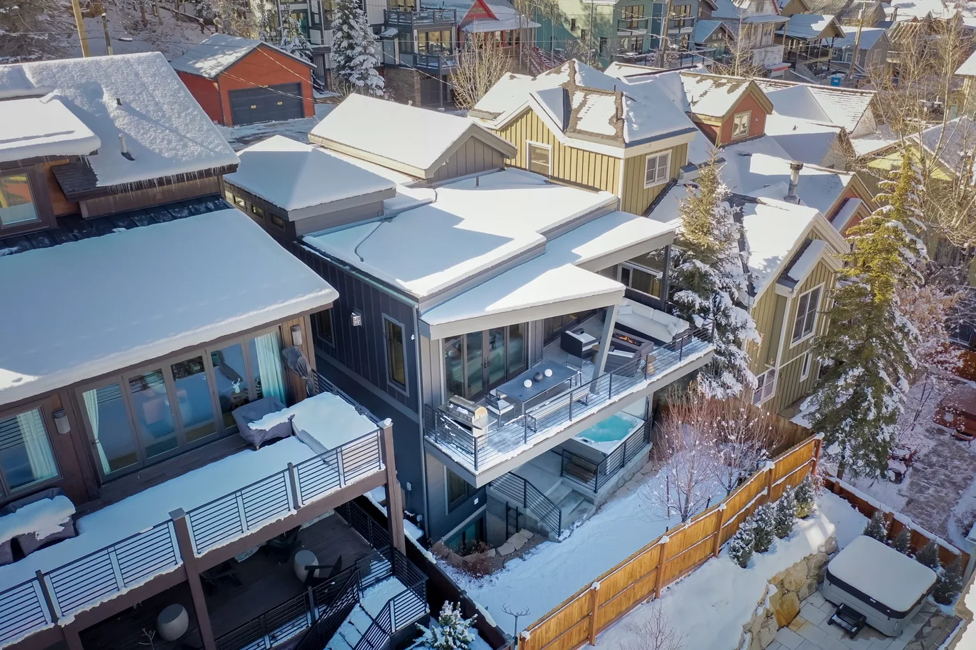 Snow-covered homes with balconies and rooftops in a residential neighborhood.