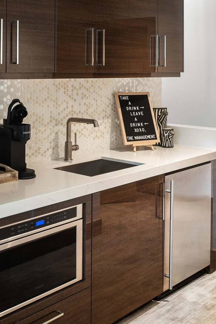 A modern kitchen with dark wood cabinets, a sink, and a built-in oven.