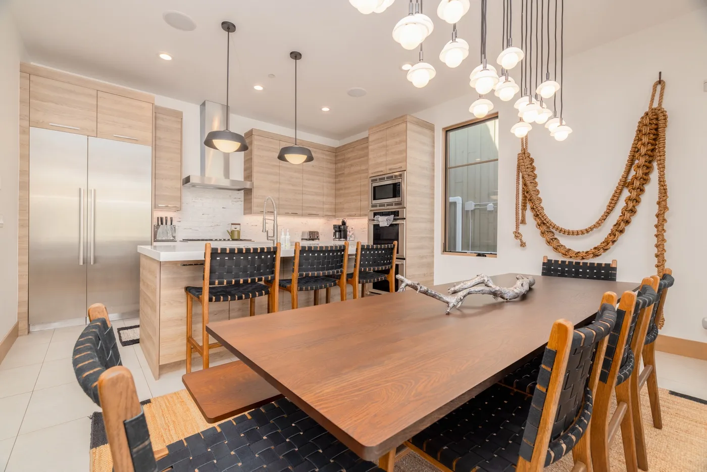 A dining area with a large wooden table and a kitchen in the background.