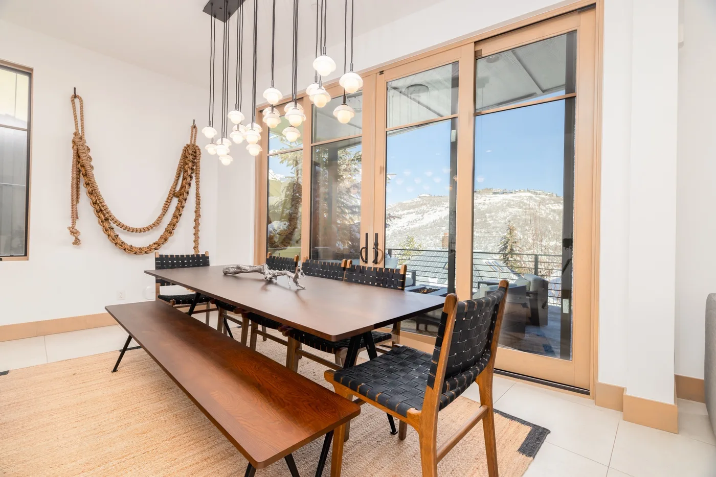 A dining area with a long table and windows overlooking a mountain landscape.