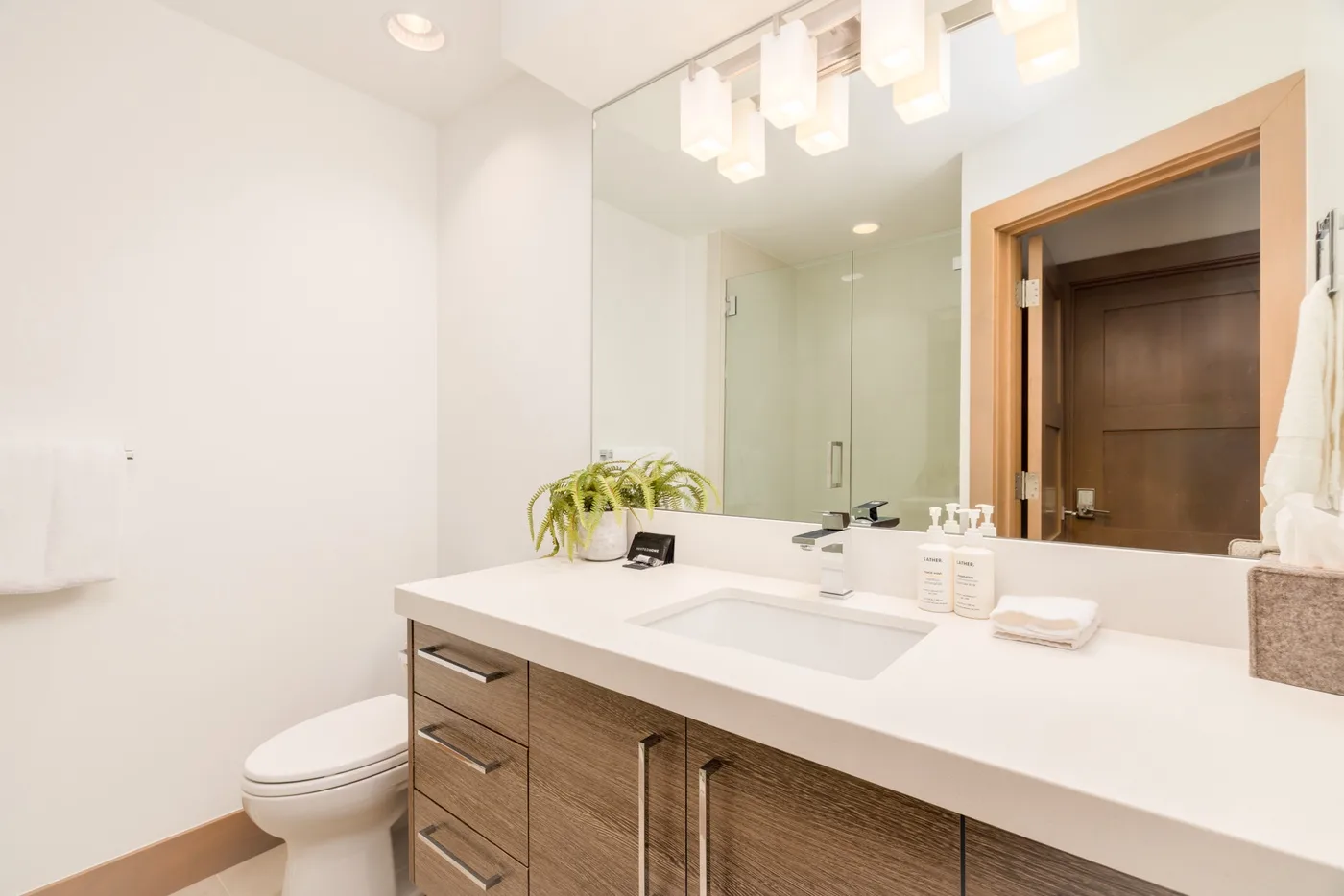 A bright bathroom vanity with a wide mirror and white countertop.
