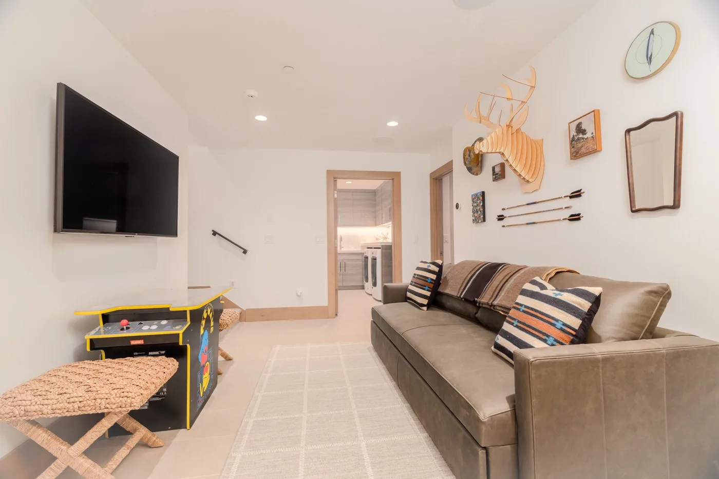A living room with a sofa, wall-mounted television, and a small game table.