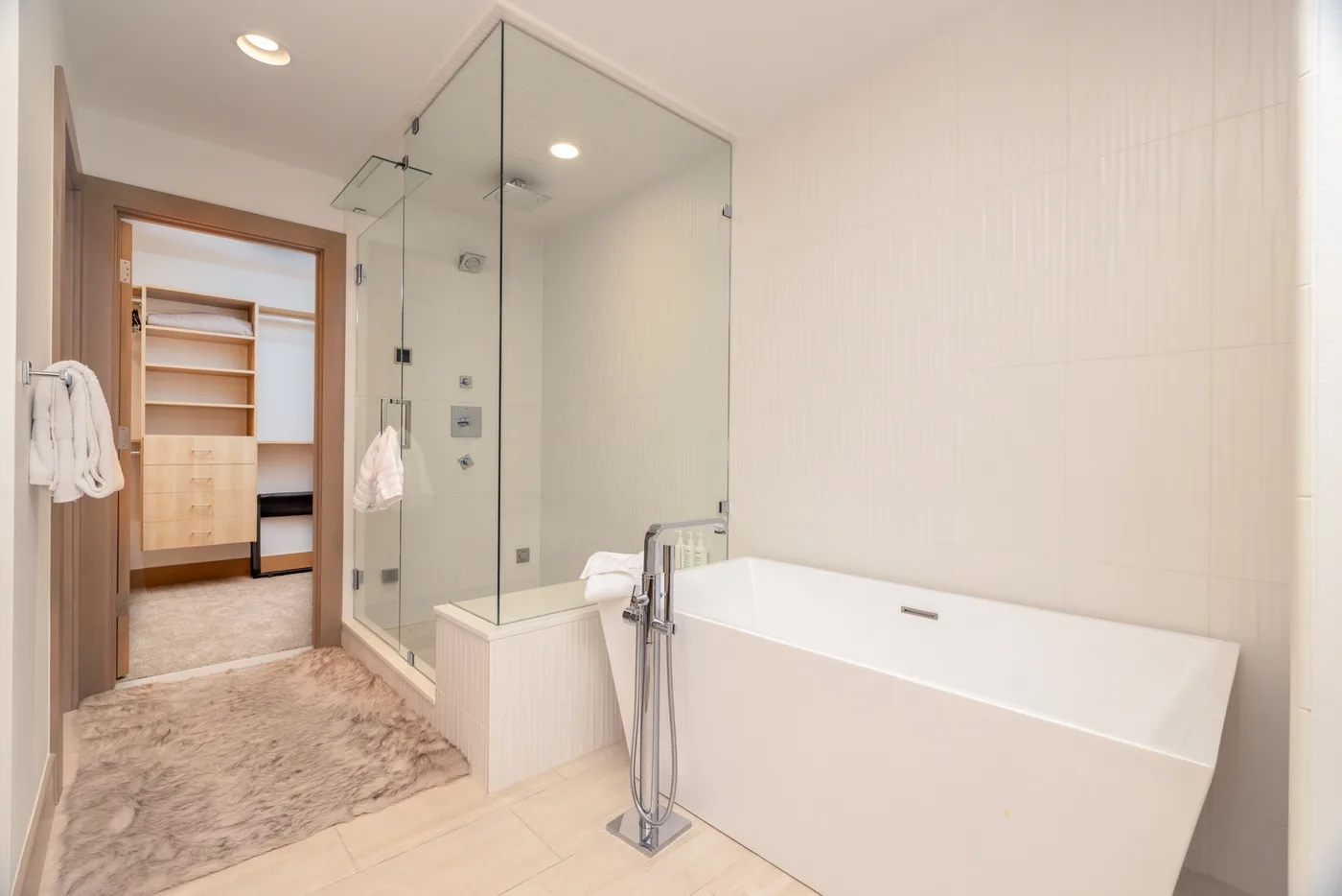 A bright bathroom with a bathtub and glass shower area.
