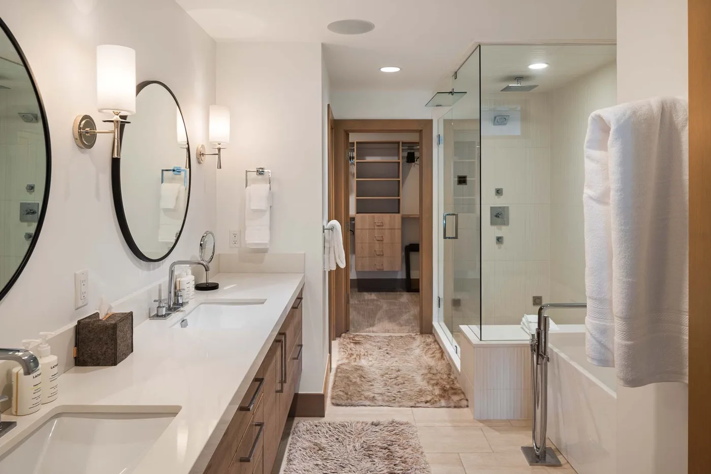 A bright bathroom with a long vanity and a glass-enclosed shower.