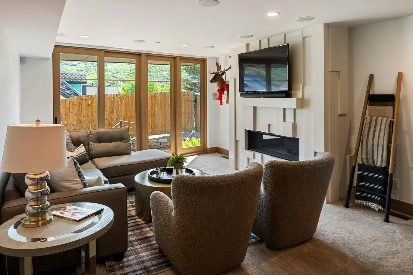 A living room with seating arranged around a coffee table beside wide glass doors.
