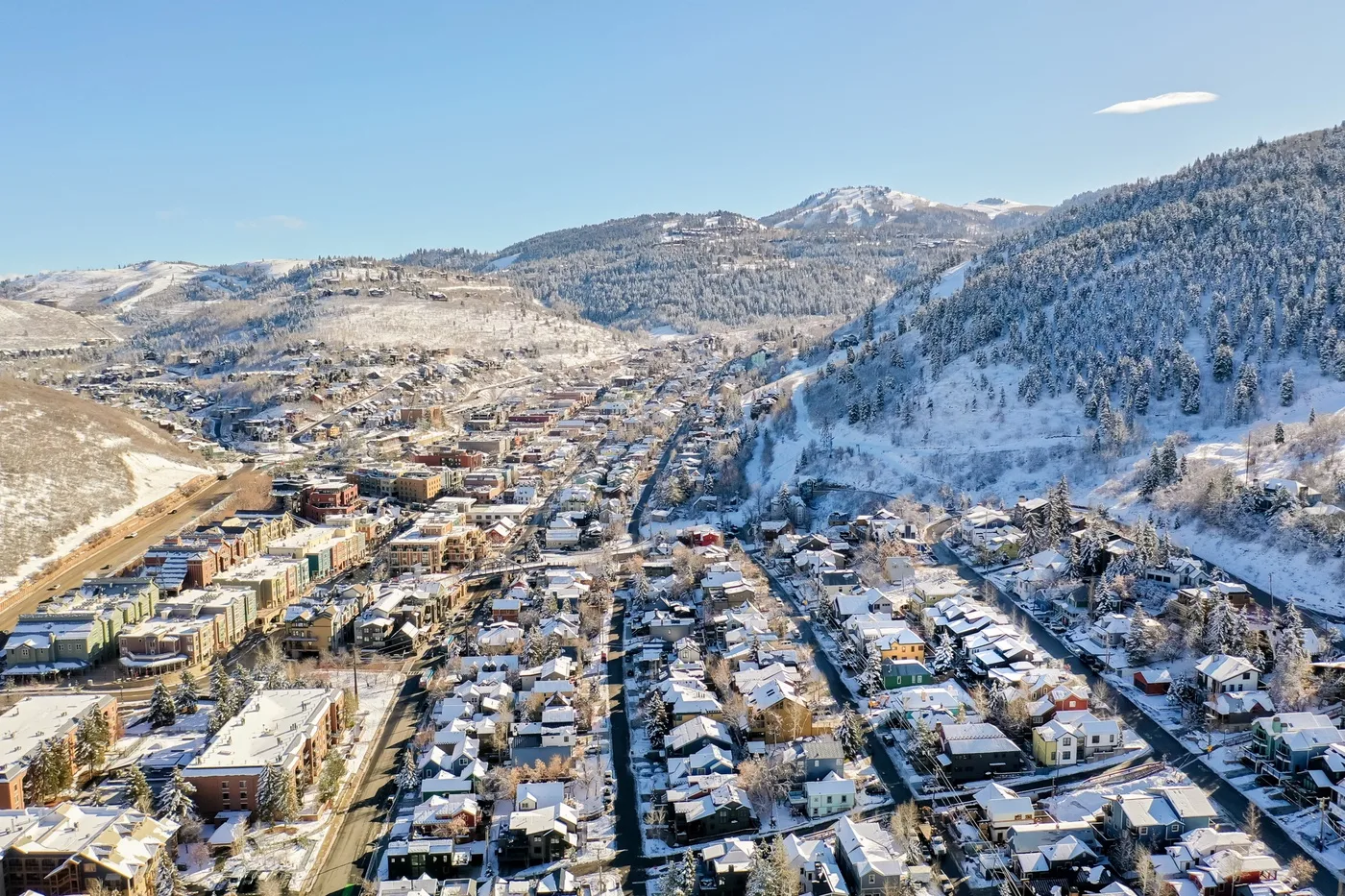 A snow-covered town spreads through a mountain valley beneath a clear sky.