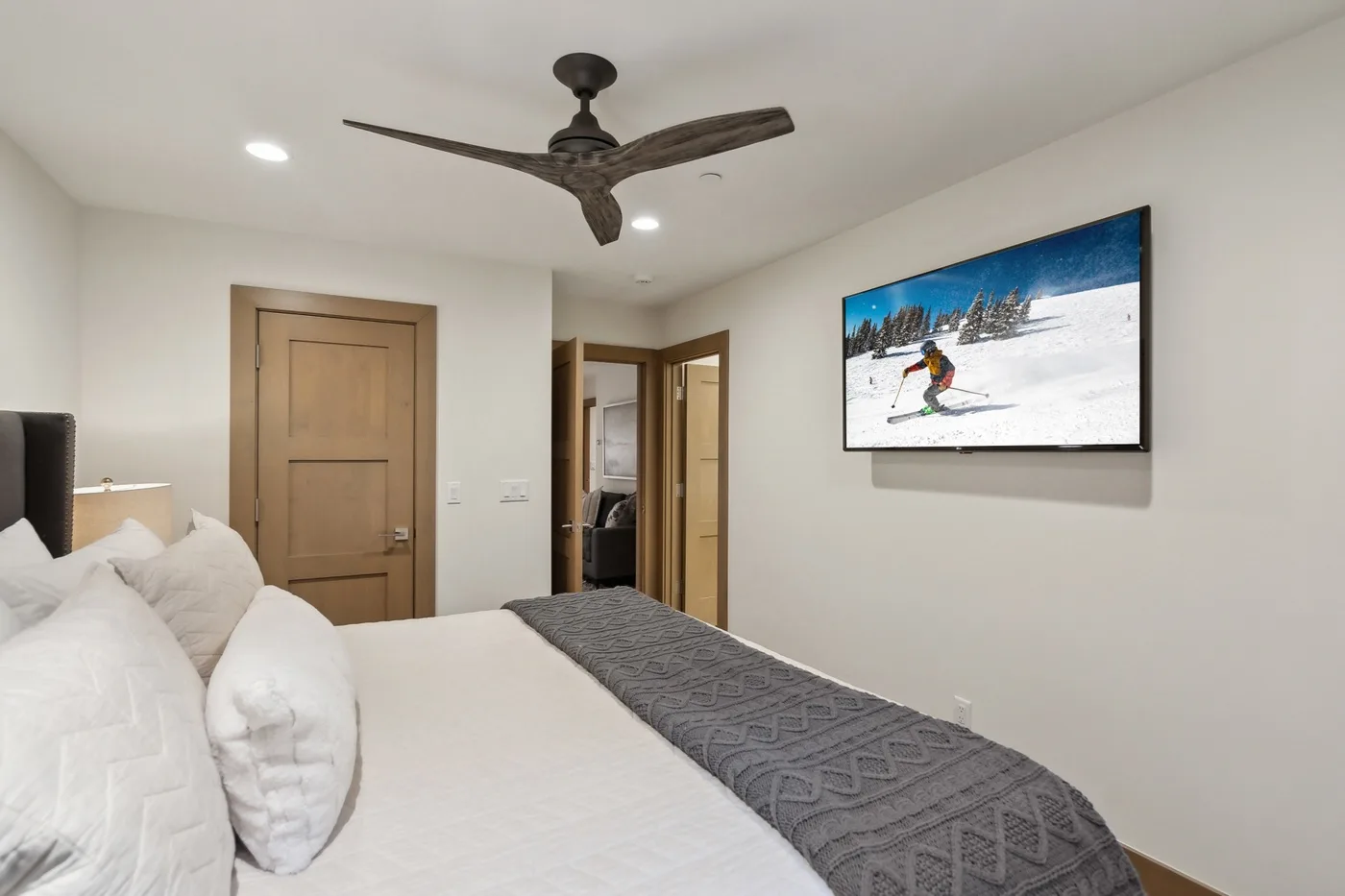A bedroom with a neatly made bed and a television mounted on the wall.