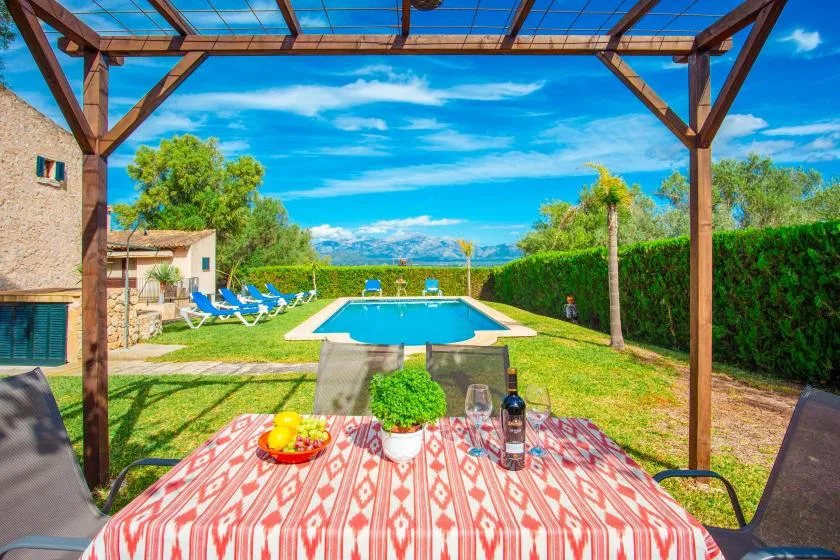 Un patio con piscina, tumbonas y una mesa de comedor a la sombra.