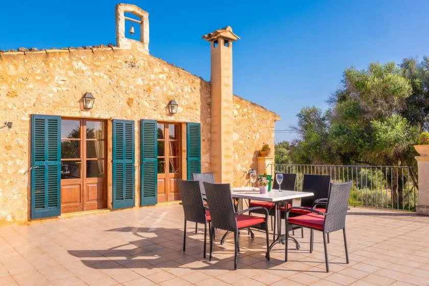 Una casa de piedra da a un patio embaldosado con asientos al aire libre.
