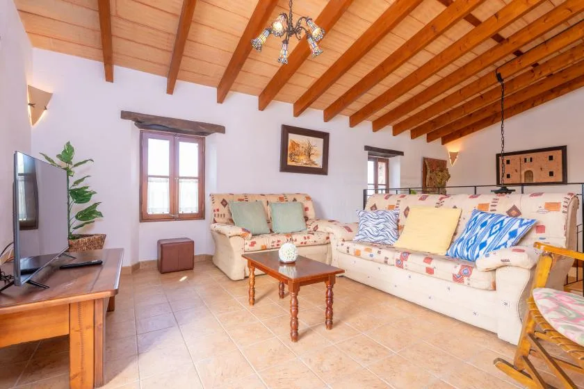 Una sala de estar con asientos, una mesa de centro y vigas de madera a la vista.