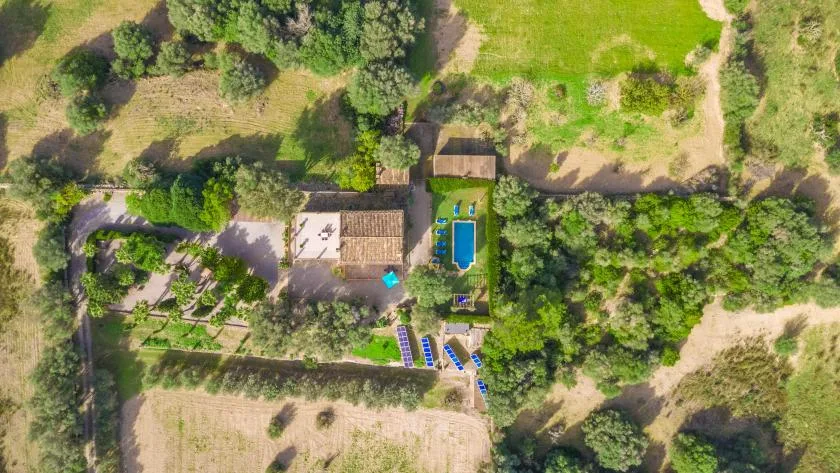Una vista aérea muestra una propiedad verde rodeada de árboles y campos abiertos.